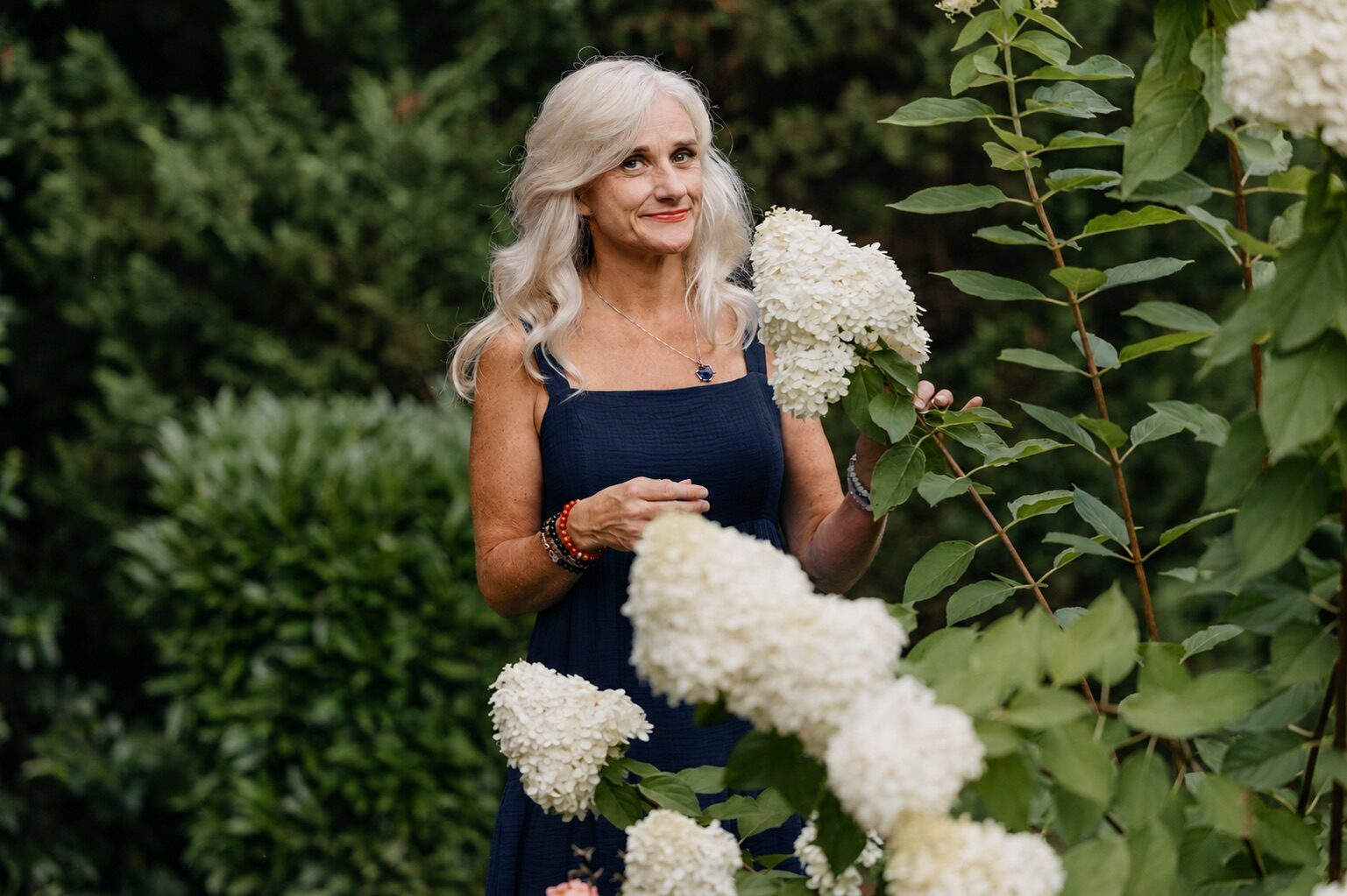 Helen Armstrong standing among white hydrangeas.